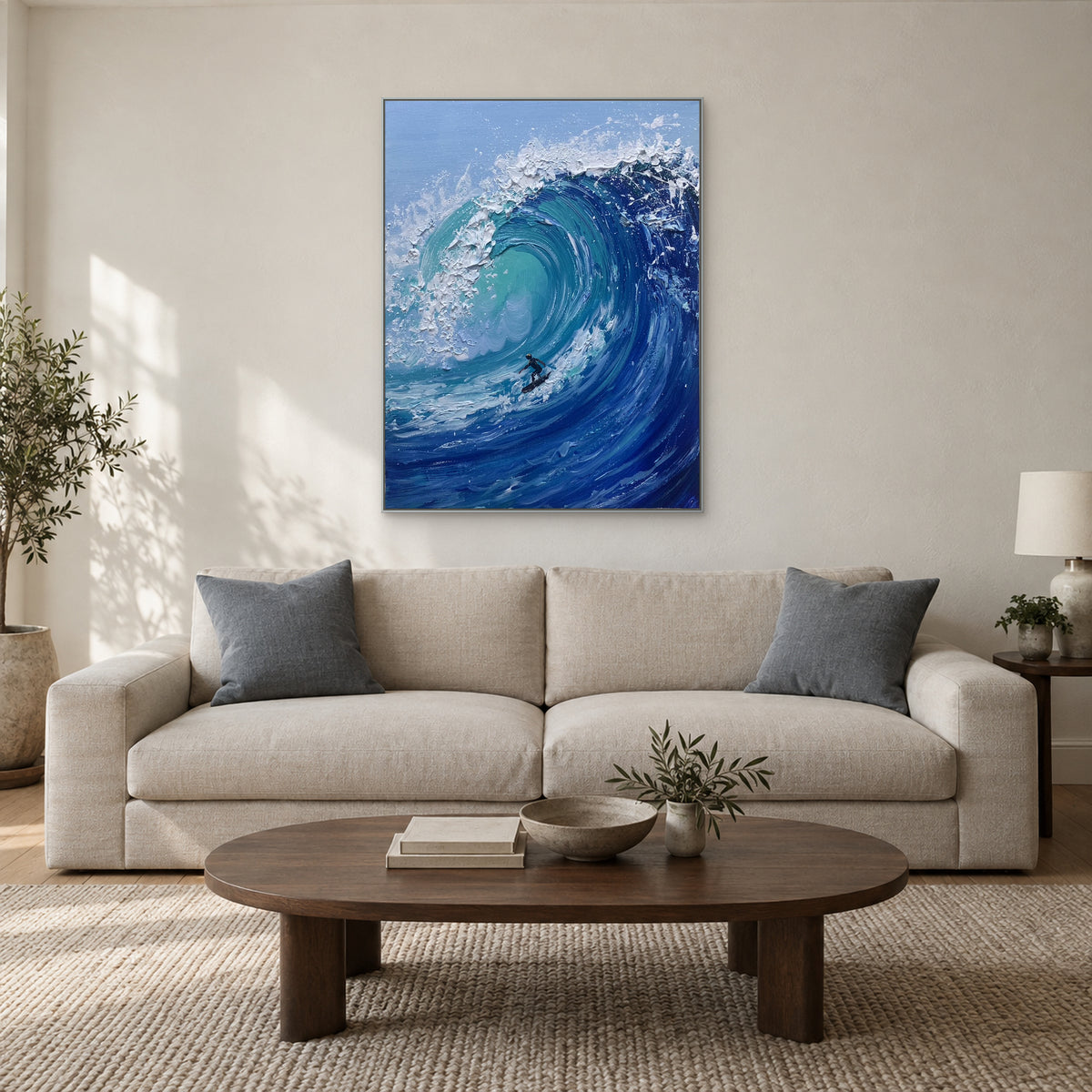 Silver-tone framed blue wave painting above a cream sofa with blue-grey cushions and an oval coffee table