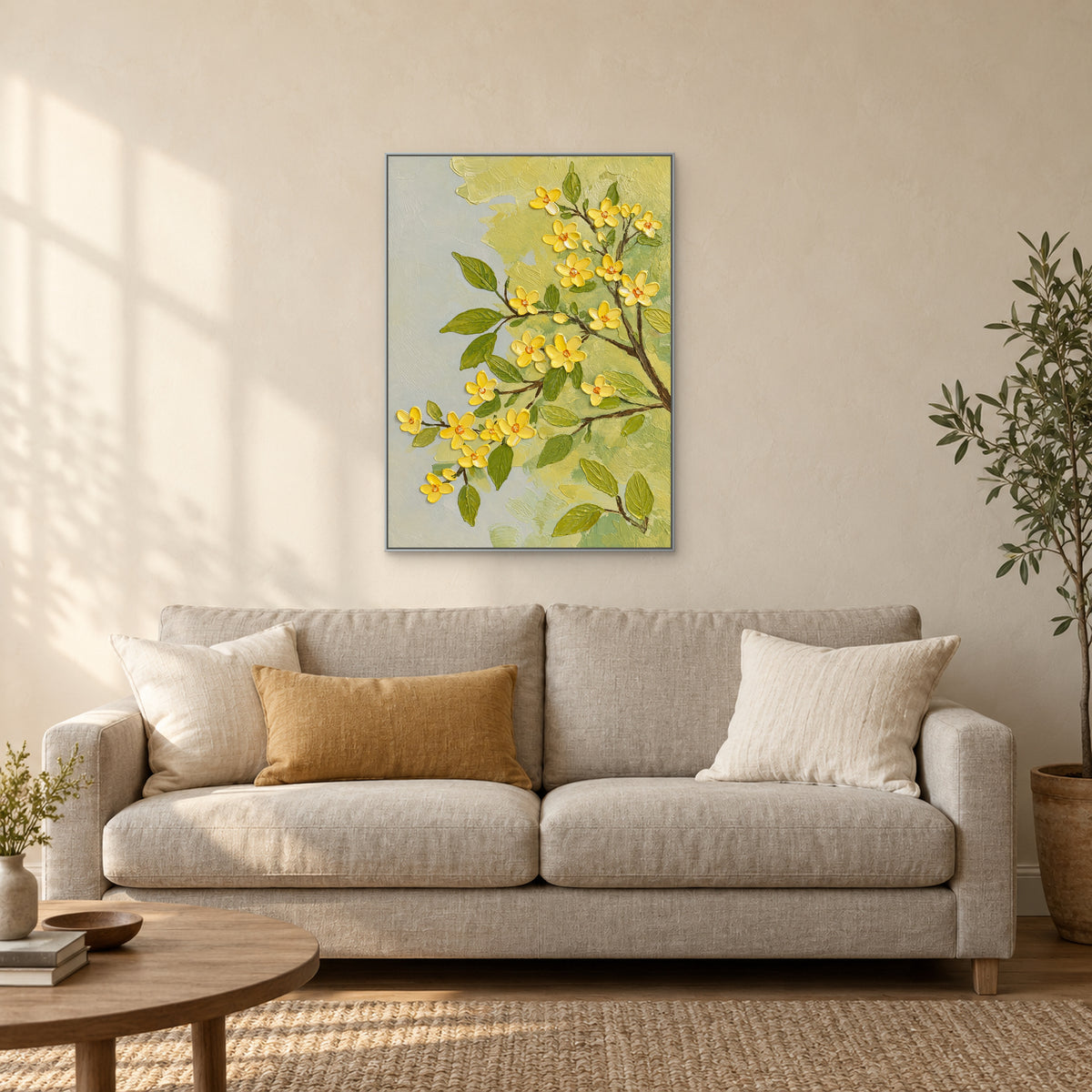 Tableau floral dans un cadre argenté, au-dessus d’un canapé crème avec un coussin ocre et une table basse en bois