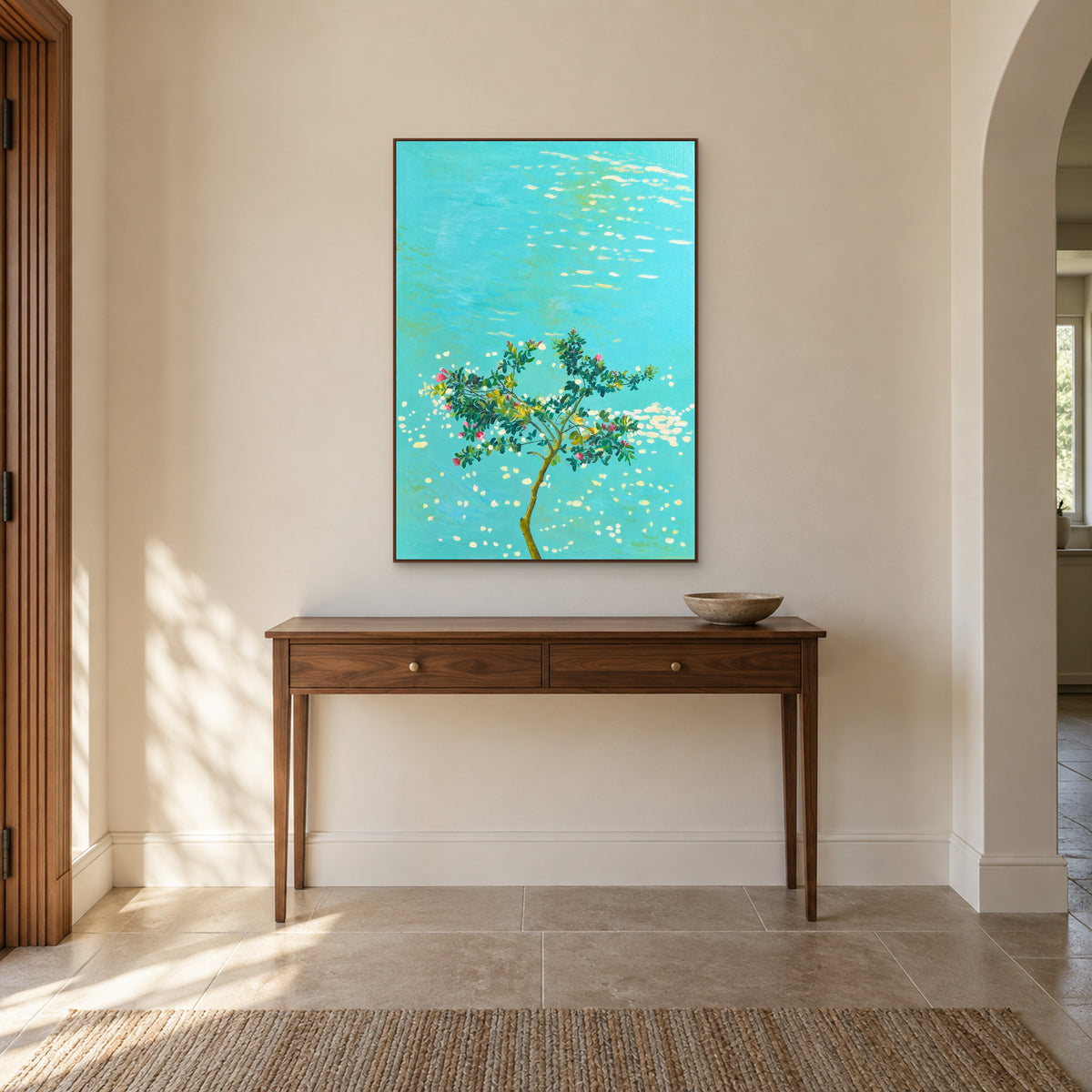 Arbre à fleurs roses et eau turquoise dans un cadre flottant ton noyer, au-dessus d’une console d’entrée en bois