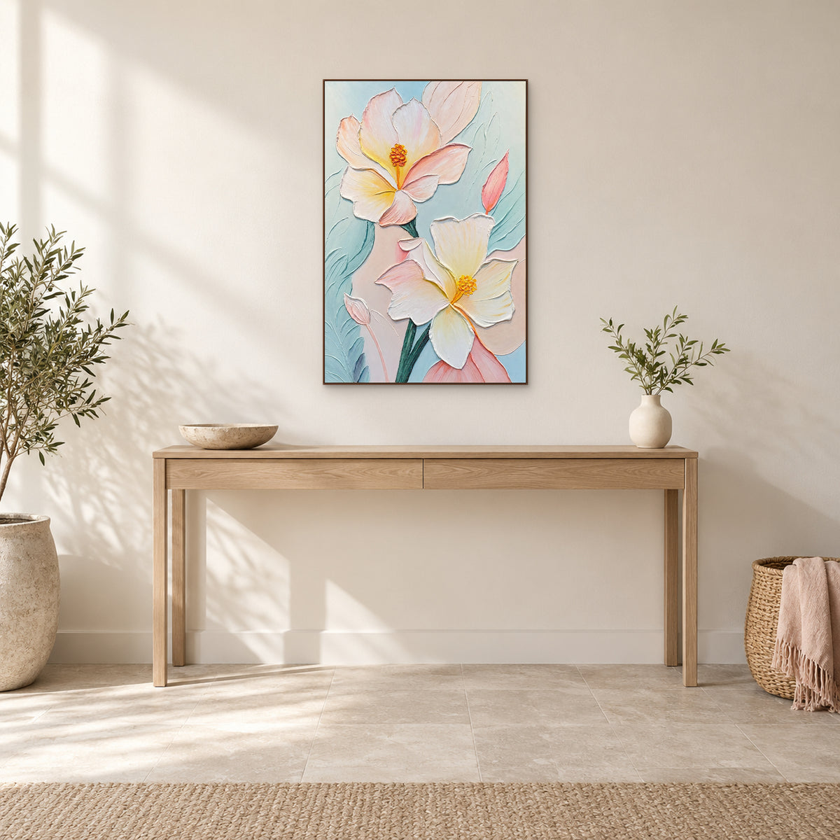 Deux grandes fleurs claires dans un cadre couleur noyer, au-dessus d’une console avec coupe en pierre et vase ivoire