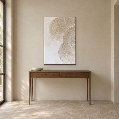 Sand and ivory concentric circles in a walnut-look frame above a slim wooden entryway console.