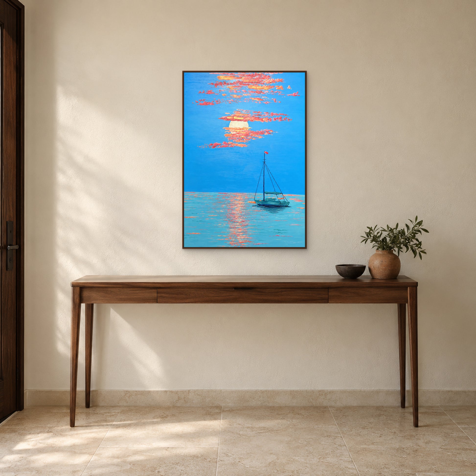 Tableau bleu et corail d’une barque au couchant, cadre flottant ton noyer, au-dessus d’une fine console d’entrée en bois.