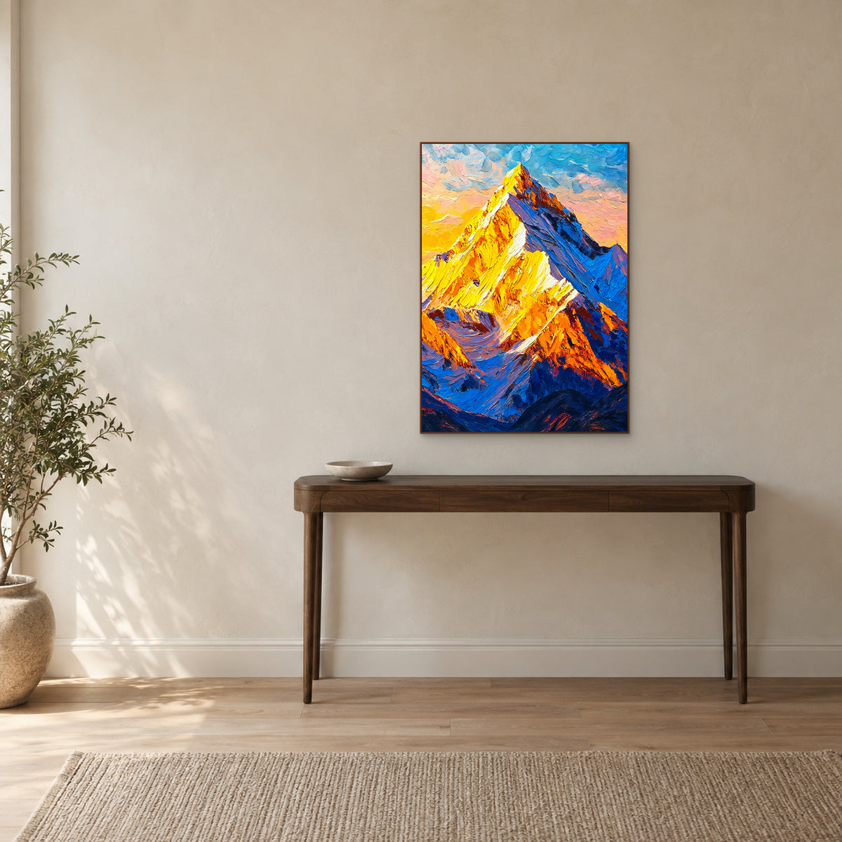 Golden mountain painting in a walnut-tone frame aligned above a slender dark wood entrance console