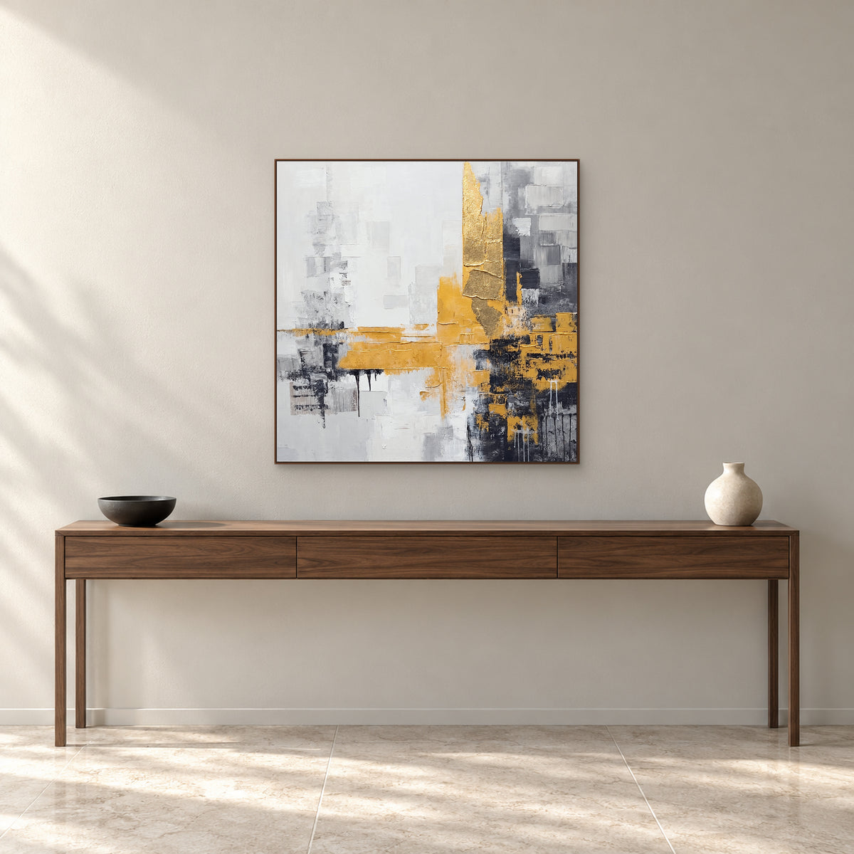 Square grey and gold painting in a walnut-tone frame above a slim walnut console with a black bowl and cream vase