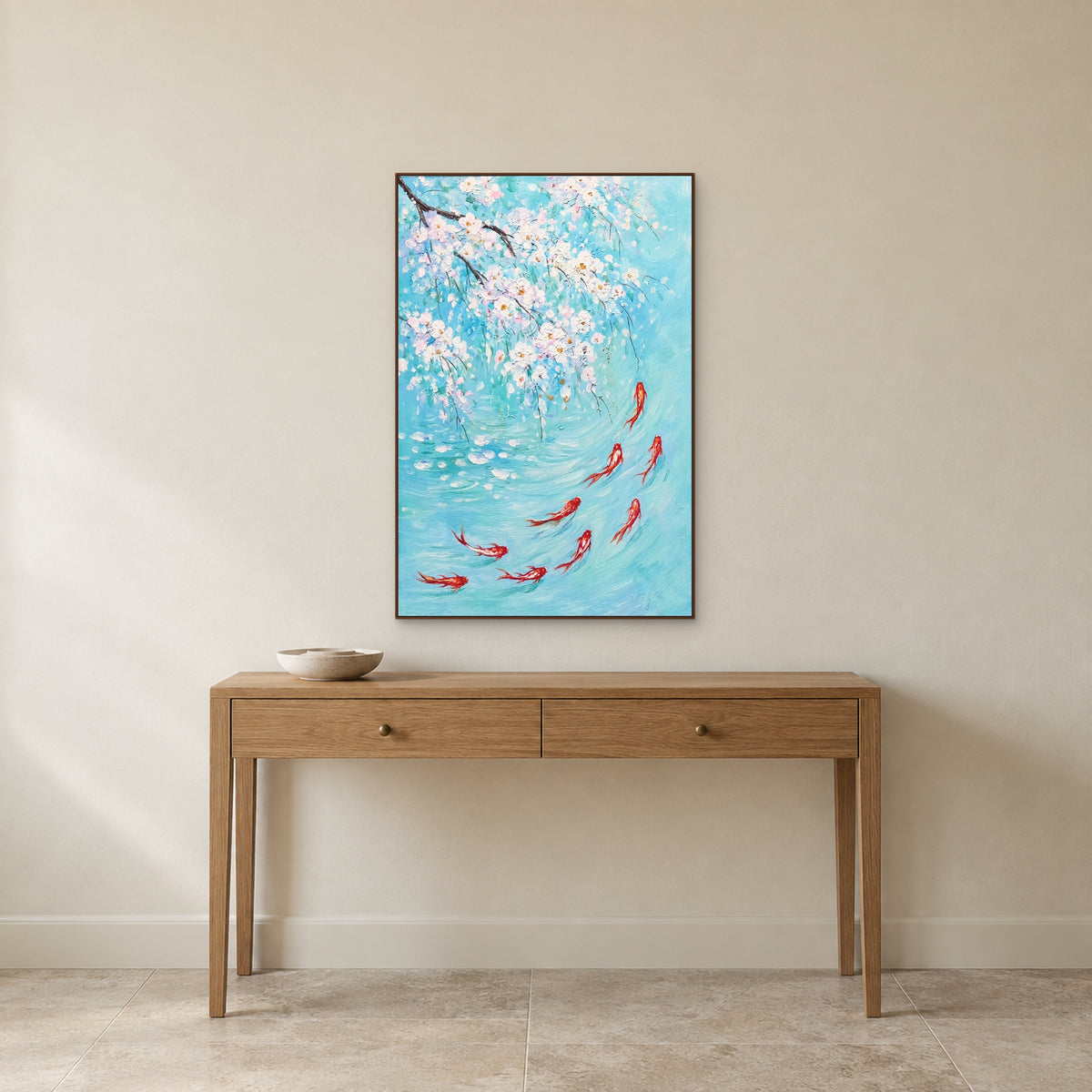 Koi and white blossom painting in a walnut-coloured floating frame centred above a slender oak console on an ivory wall.