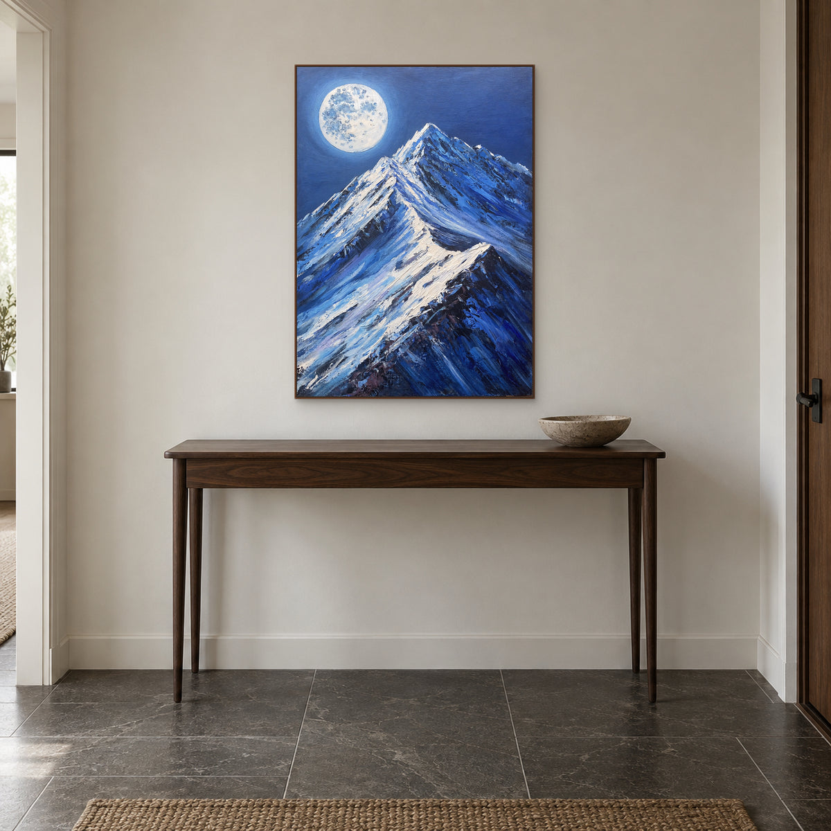 Sommets enneigés sous la lune dans un cadre ton noyer, centrés au-dessus d’une console d’entrée en bois
