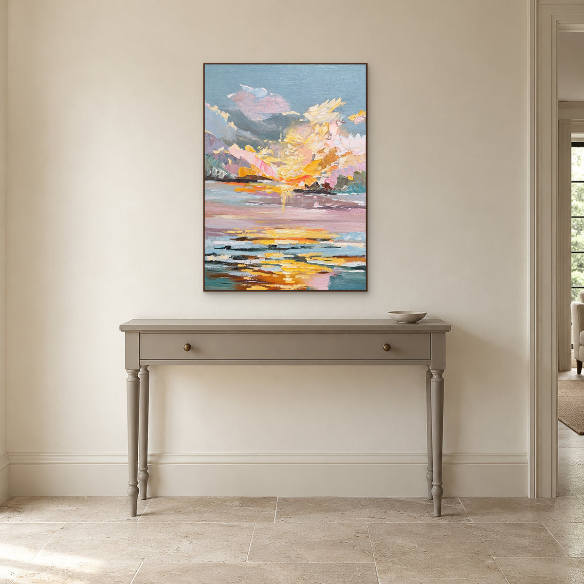 Upright sunset painting in a walnut-tone frame above a taupe entrance console