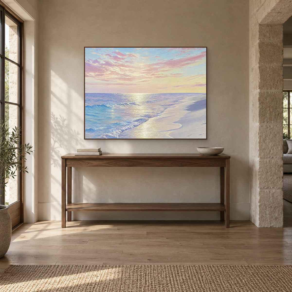 Shore of Light beach painting in a walnut-tone frame above an entryway console with a low bowl and books