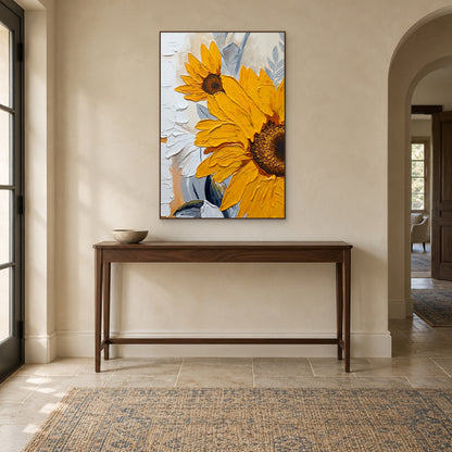 Sunflower painting in a walnut-tone frame above a slim wooden console in a cream entryway