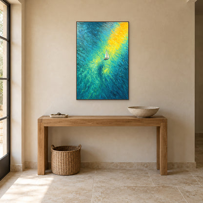 Tableau vertical de voilier et de lumière jaune sur une eau bleu-vert, cadre ton noyer au-dessus d’une console en chêne.