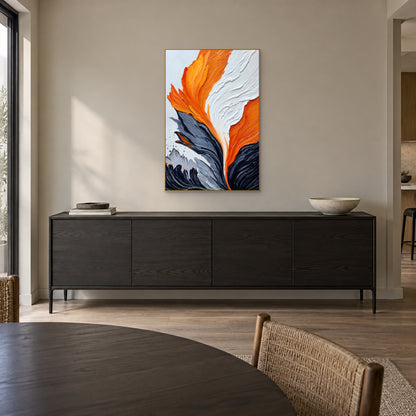 Tableau texturé orange et blanc dans un cadre champagne, au-dessus d’un buffet foncé dans une salle à manger