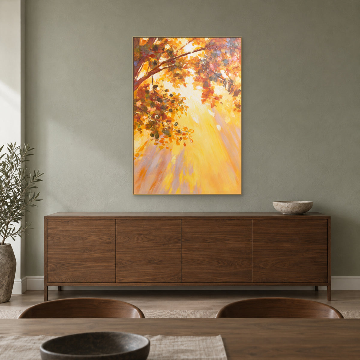 Golden foliage painting in a champagne-coloured floating frame above a walnut-toned dining room sideboard.