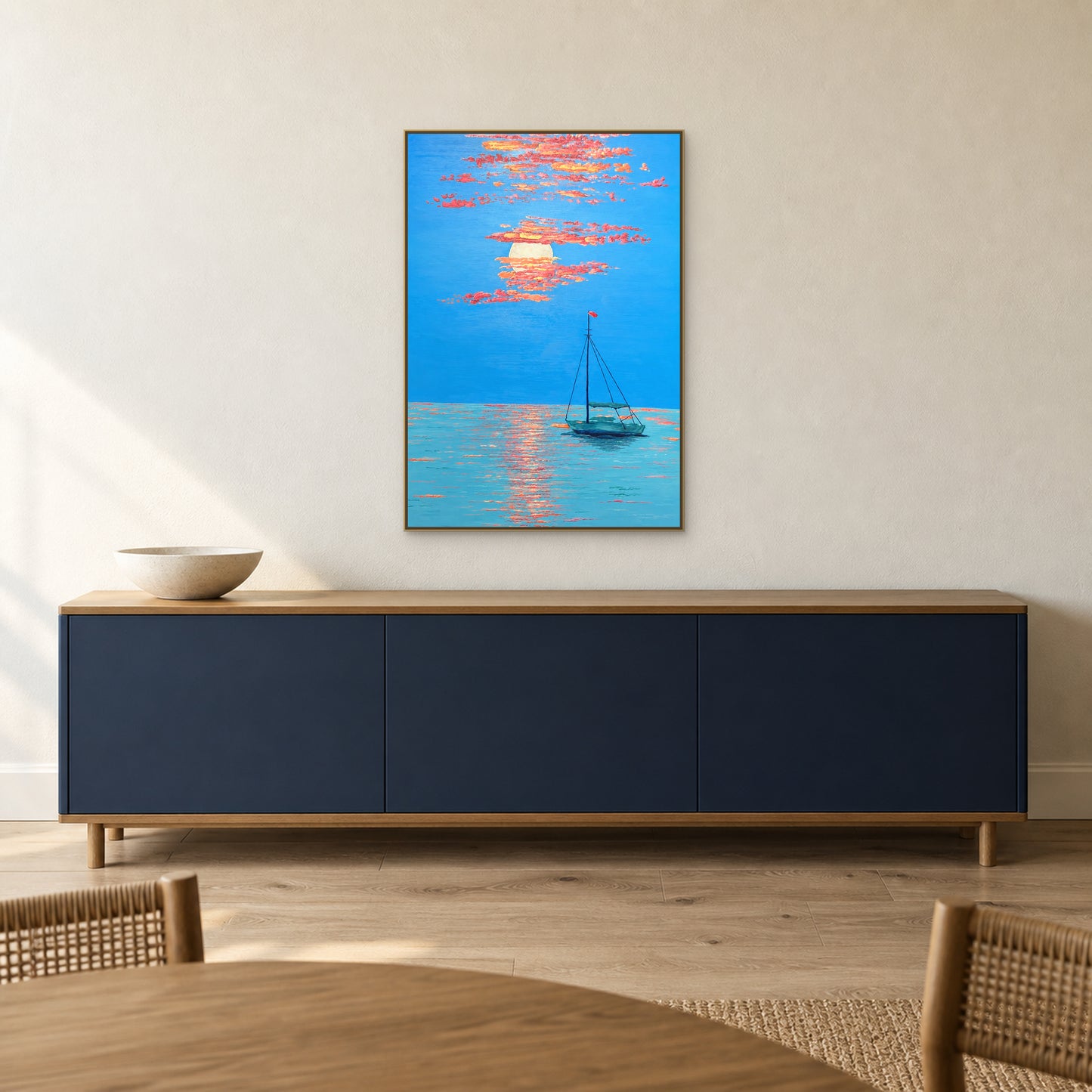 Paysage marin avec barque au couchant, cadre flottant champagne, au-dessus d’un buffet bleu marine dans une salle à manger chaleureuse.