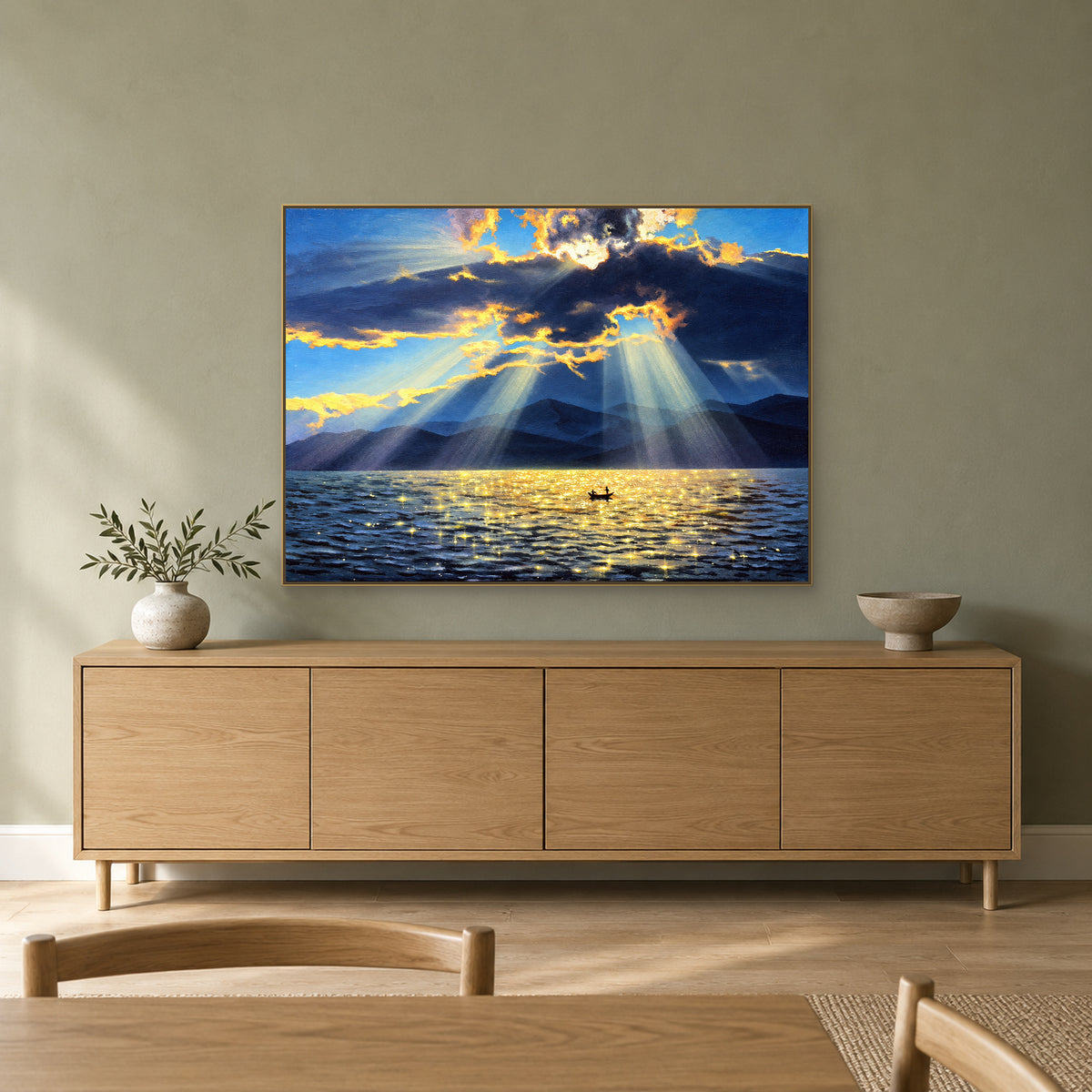 Blue and gold lake artwork in a champagne-tone frame above a wood sideboard on a sage-green wall