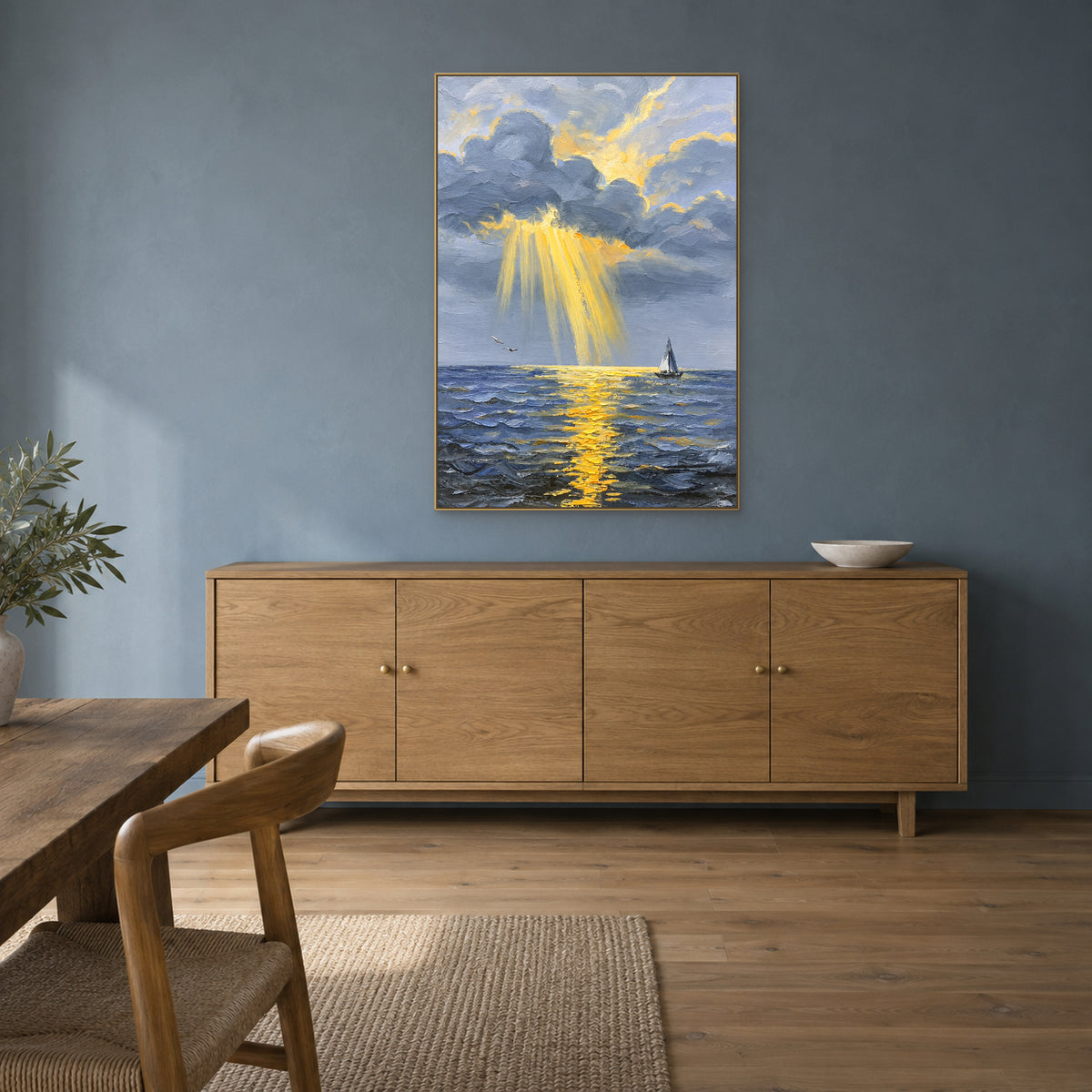 Blue-grey cloud and golden-sea painting in a champagne-tone frame above an oak sideboard.