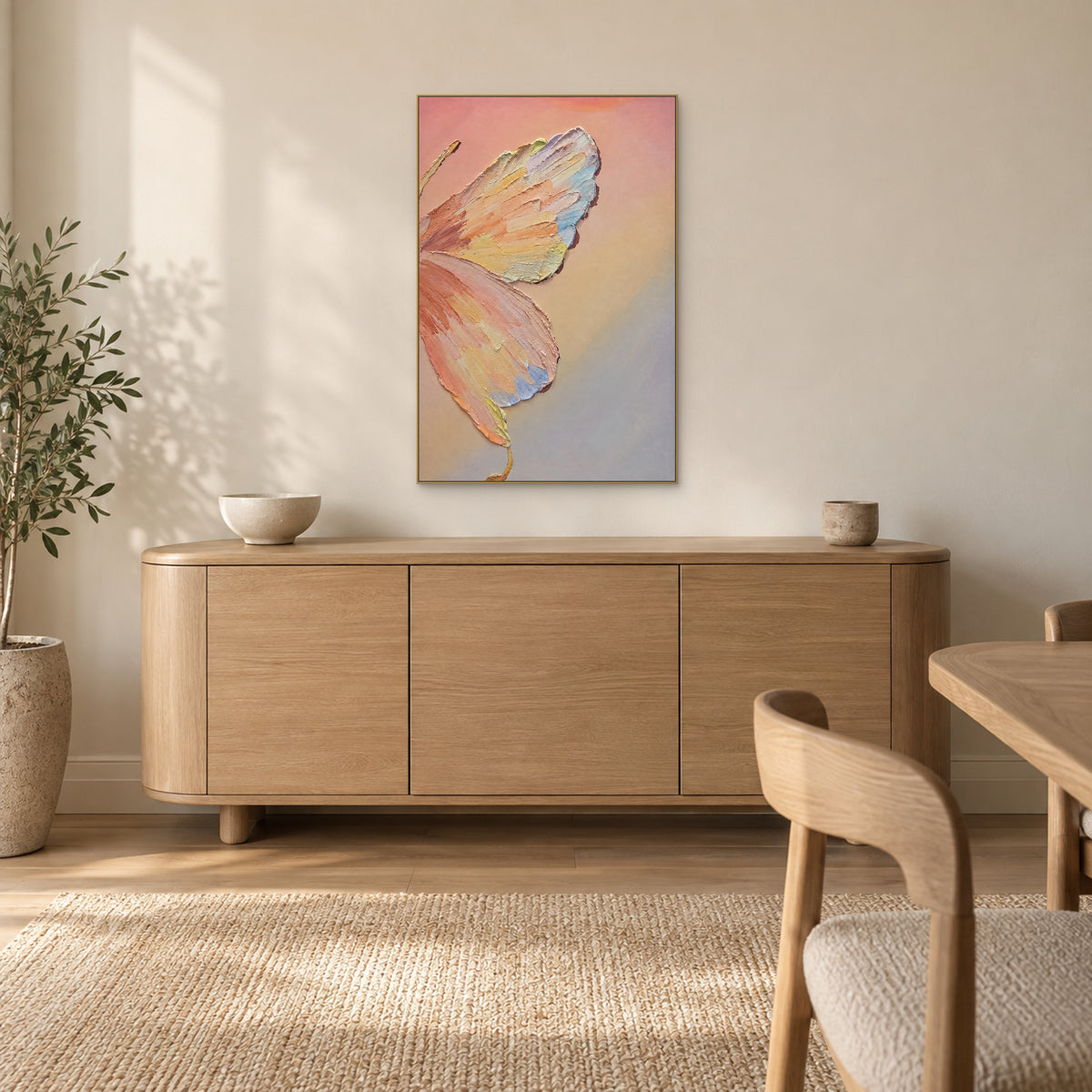 Papillon pastel dans un cadre flottant champagne au-dessus d’un buffet arrondi ton chêne