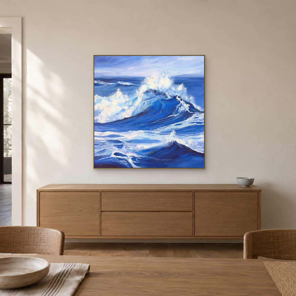 Champagne-framed periwinkle wave painting above an oak sideboard in a quiet dining room