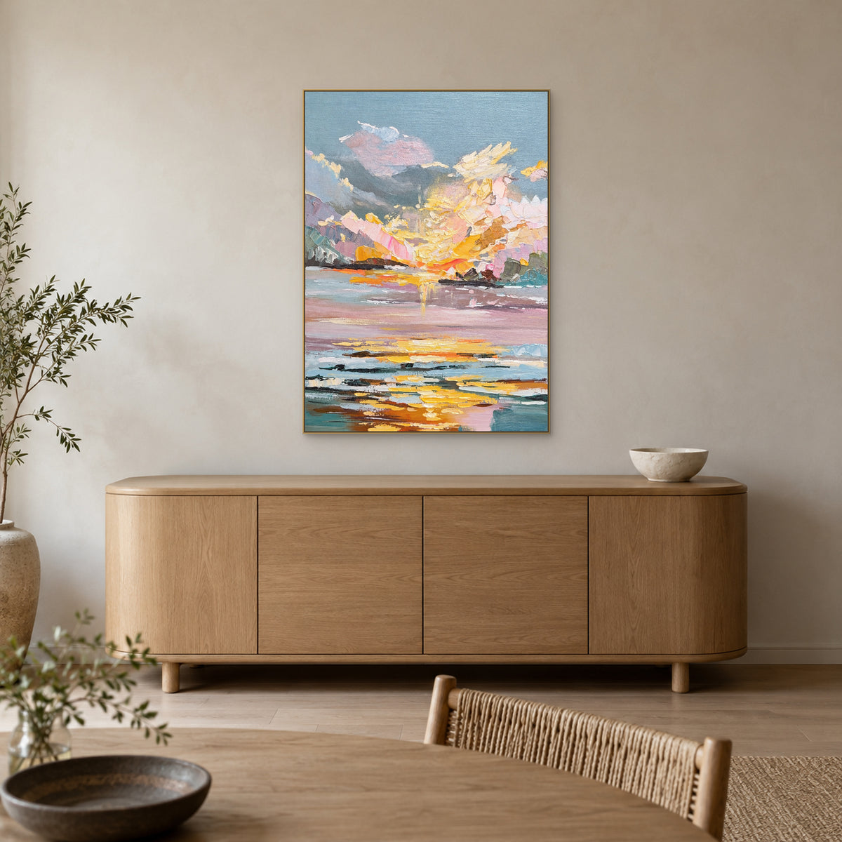 Pastel sunset artwork in a champagne-tone frame above an oak sideboard in a dining area