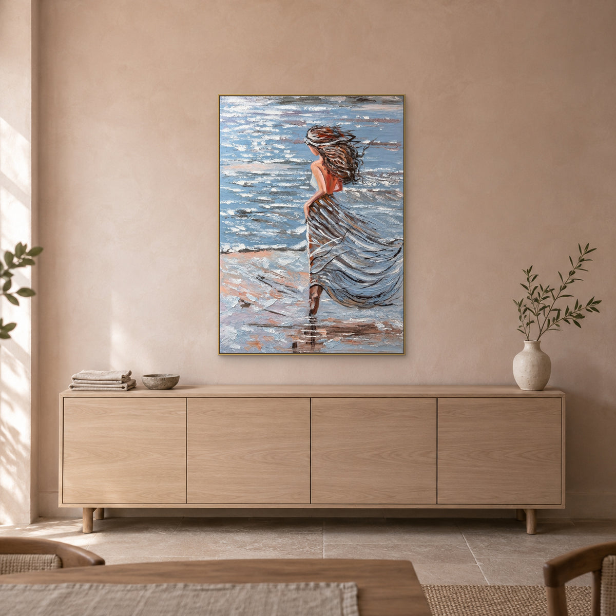 Femme au bord de mer dans un cadre flottant champagne, au-dessus d'un buffet ton chêne clair devant un mur beige rosé