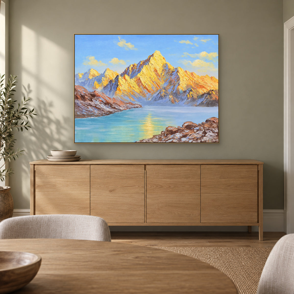 Tableau de lac et de montagnes dorées dans un cadre champagne, au-dessus d'un buffet de salle à manger en bois clair