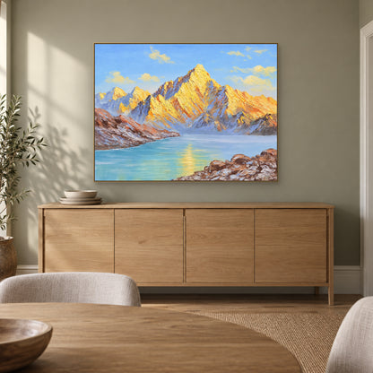 Tableau de lac et de montagnes dorées dans un cadre champagne, au-dessus d'un buffet de salle à manger en bois clair