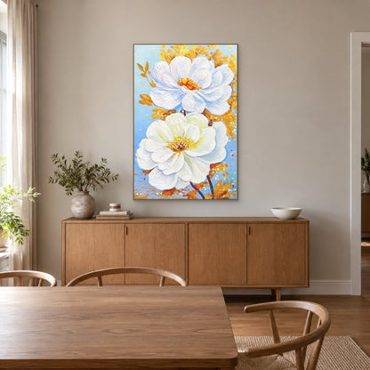 White and gold flowers in a champagne-coloured floating frame above a wood sideboard in a sunlit dining room.