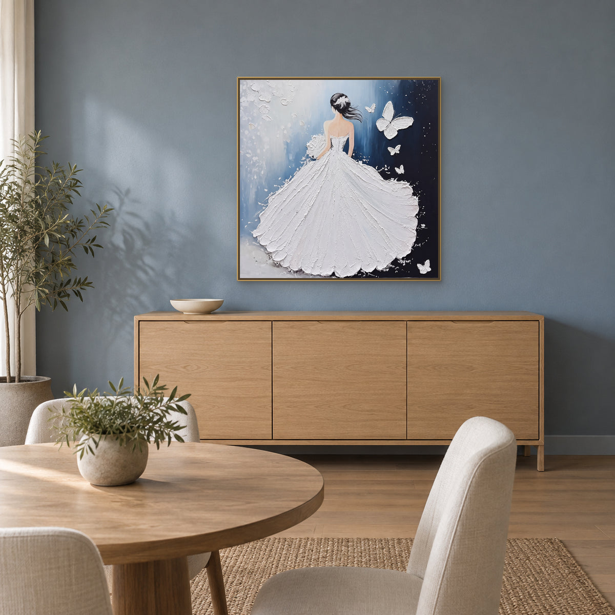Blue and white gown painting in a champagne-tone frame above a sideboard on a blue dining room wall