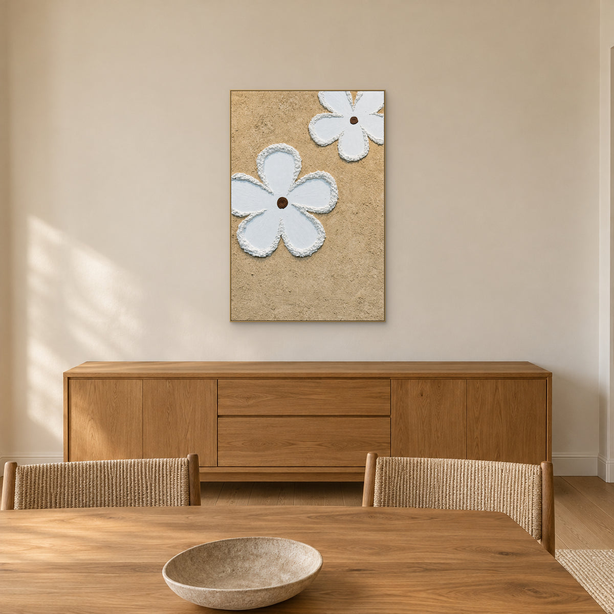 White flowers on a granular beige ground in a champagne-coloured frame above a wooden dining-room sideboard