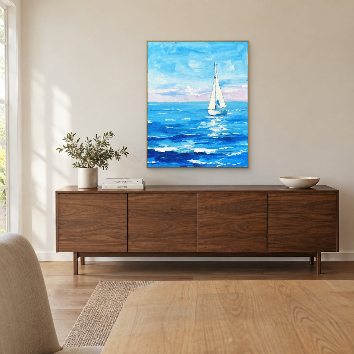 Hand-painted blue sailboat seascape in a champagne-tone frame above a walnut-look dining-room sideboard.