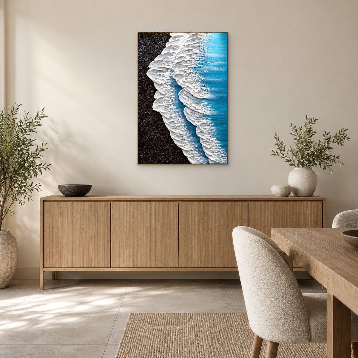 Vertical wave painting in a champagne-tone frame above a wooden sideboard beside a dining table