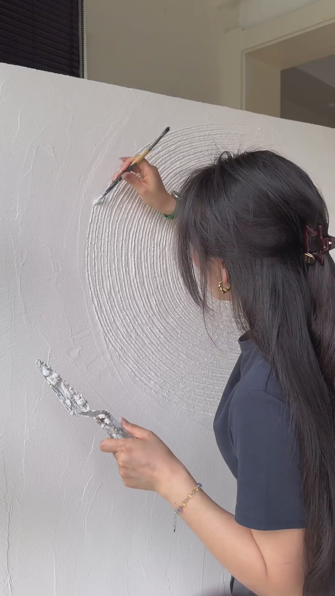 Hand-carving and colouring circular relief, touching the finished texture, and showing the neutral artwork in a room.