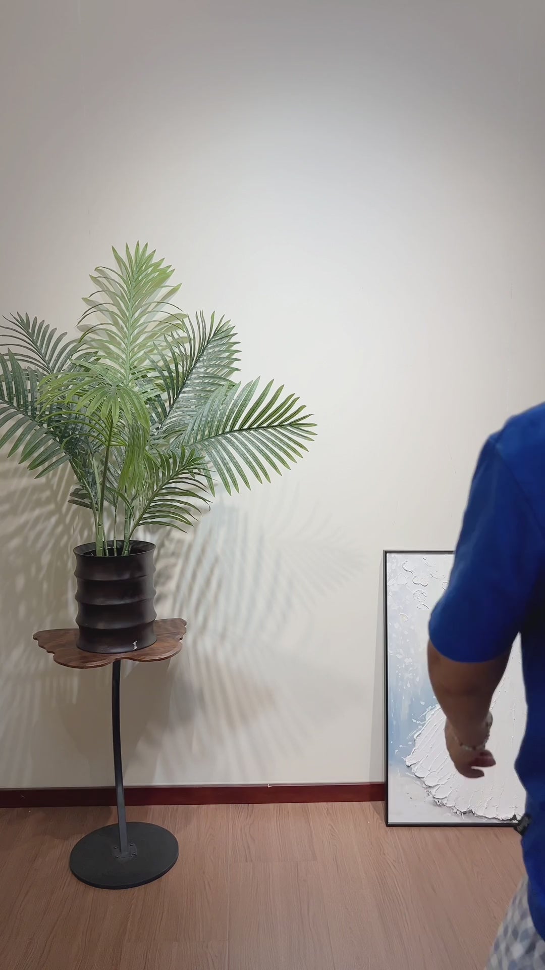 Studio video of a person walking over to pick up the white gown and butterfly painting, followed by its front reveal with gentle guitar music
