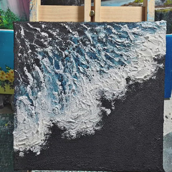 A square blue wave painting shown on an easel, then created through charcoal ground, white foam and fine blue brush marks