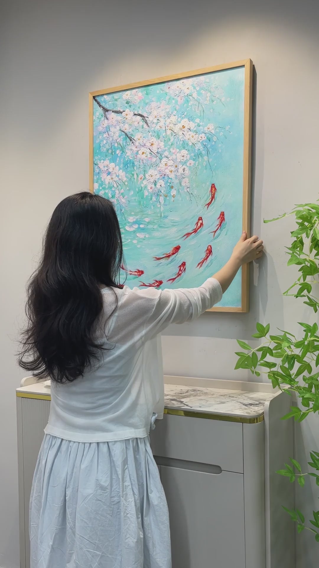 Framing and handling of the koi painting, a close view of raised white blossoms, a hand tracing the koi and a finished wall display.